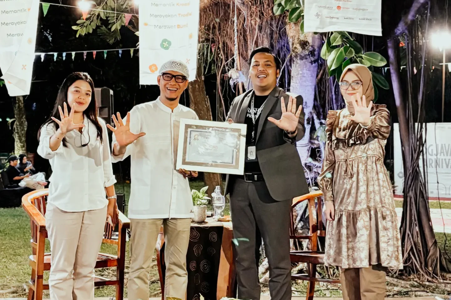Empat orang berpose dengan gestur lima jari, salah satunya memegang piagam penghargaan